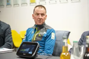 Ein Mann sitzt bei einem Tisch und blickt nach links.