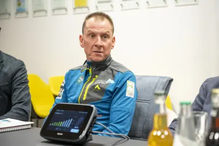 Ein Mann sitzt bei einem Tisch und blickt nach links.