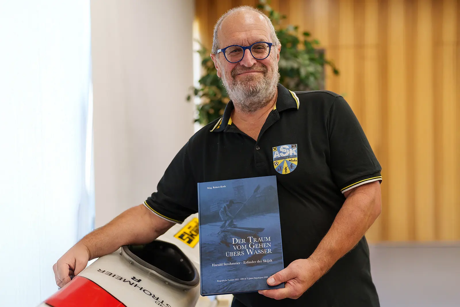 EIn Mann mit Brille und Bart hält ein Buch