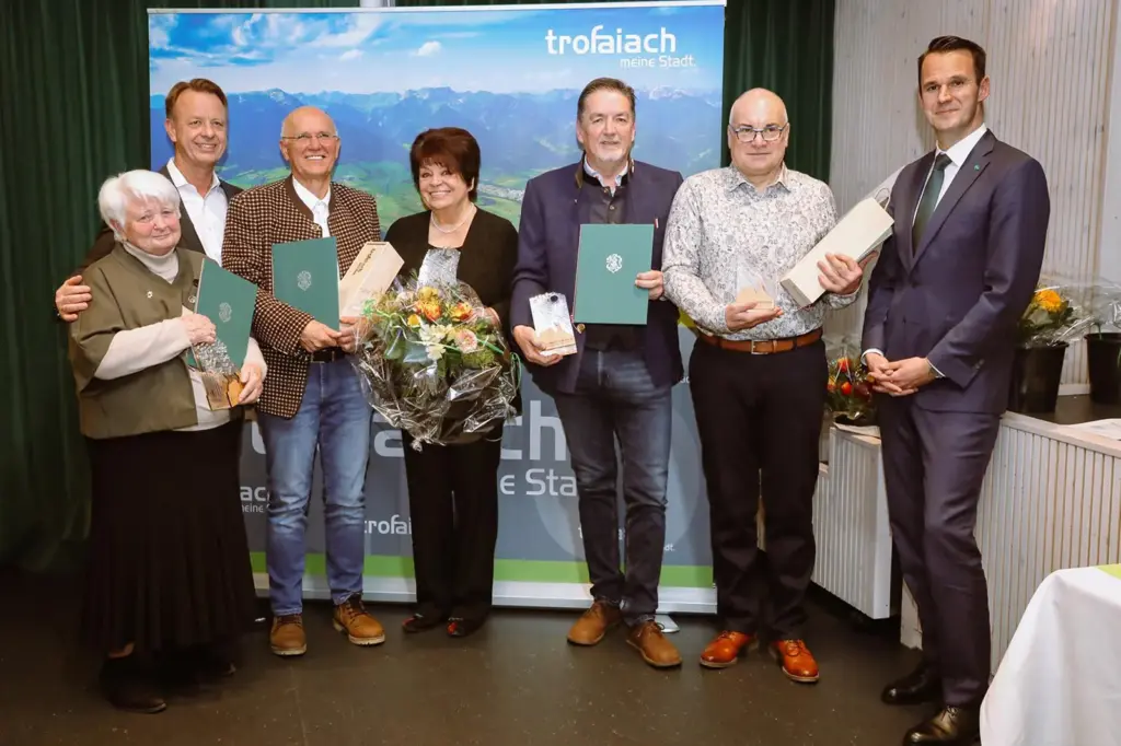 Sieben Personen mit Preisen, Blumen und Urkunden