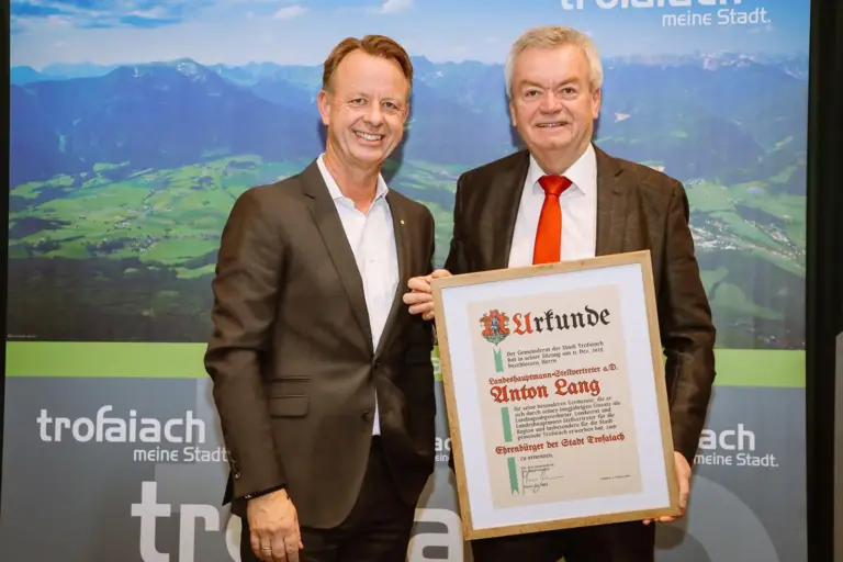 Zwei Männer im Anzug mit einer Urkunde