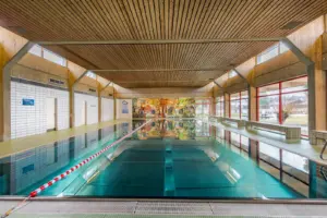 Ein Hallenbad mit großem Becken und Holzdecke