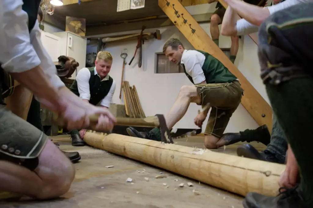 Junge Männer in Tracht beim Holzhacken