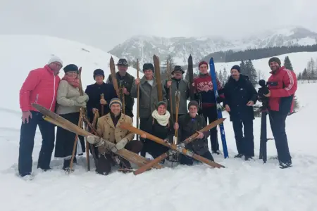Eine Gruppe von Personen in historischer Schiausrüstung im Schnee