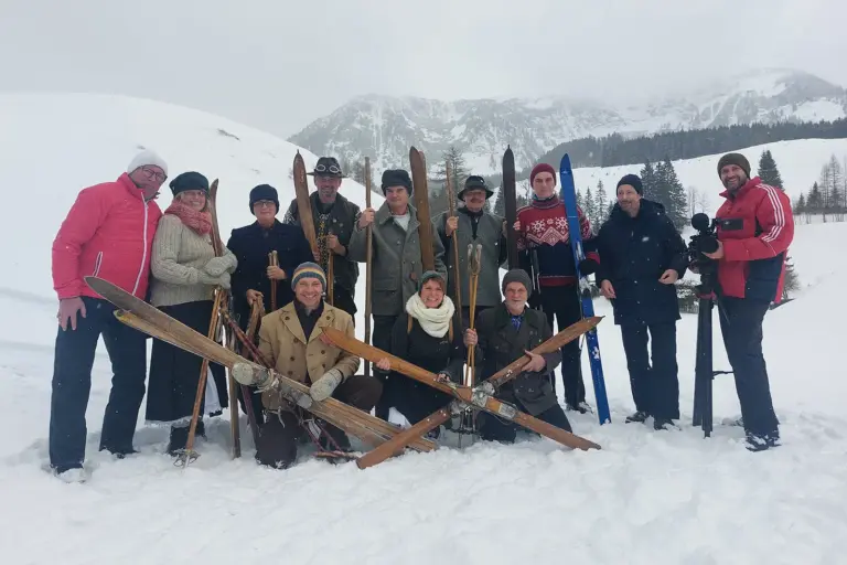 Eine Gruppe von Personen in historischer Schiausrüstung im Schnee