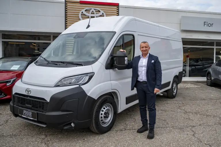 Ein Mann steht neben einem Auto.