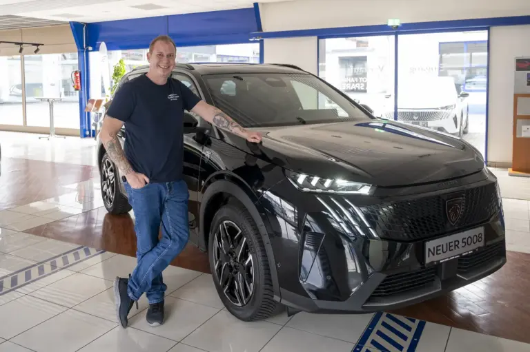 Löwe mit Strom Ein Mann steht neben einem Auto.