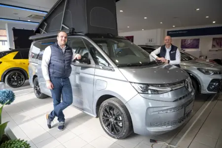 Zwei Männer stehen neben einem Auto.