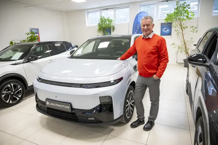 Zehnersprung Ein Mann steht neben einem Auto.