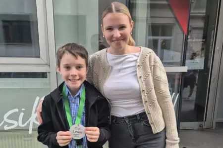 Ein Bub mit einer Medaille wird von einer jungen Frau umarmt