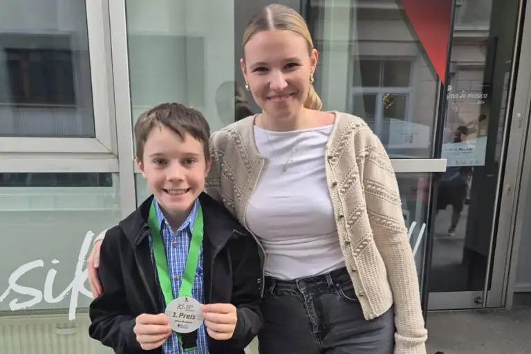 Ein Bub mit einer Medaille wird von einer jungen Frau umarmt