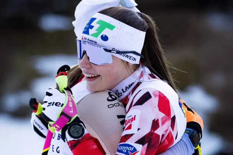 Eine junge Langläuferin umarmt freudig eine andere Langläuferin.