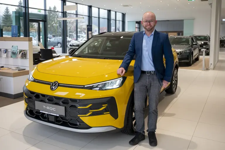 Ein Mann steht neben einem Auto.