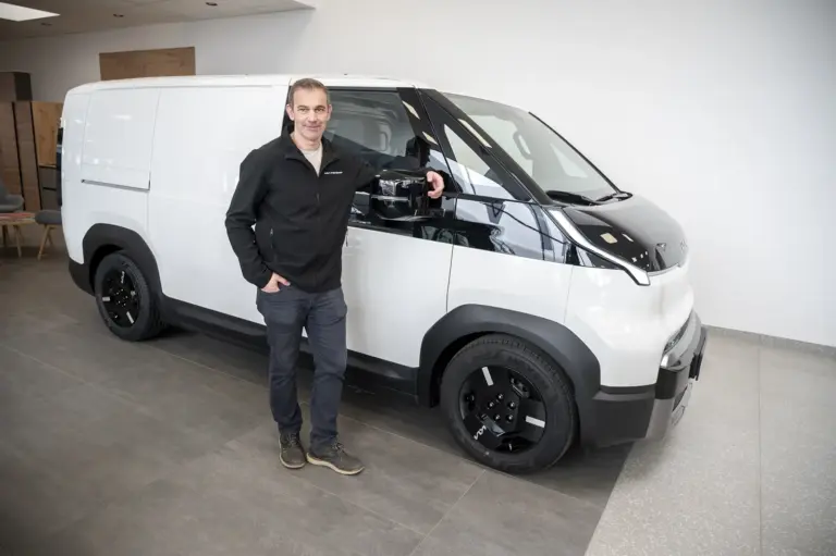 Ein Mann steht neben einem Auto.