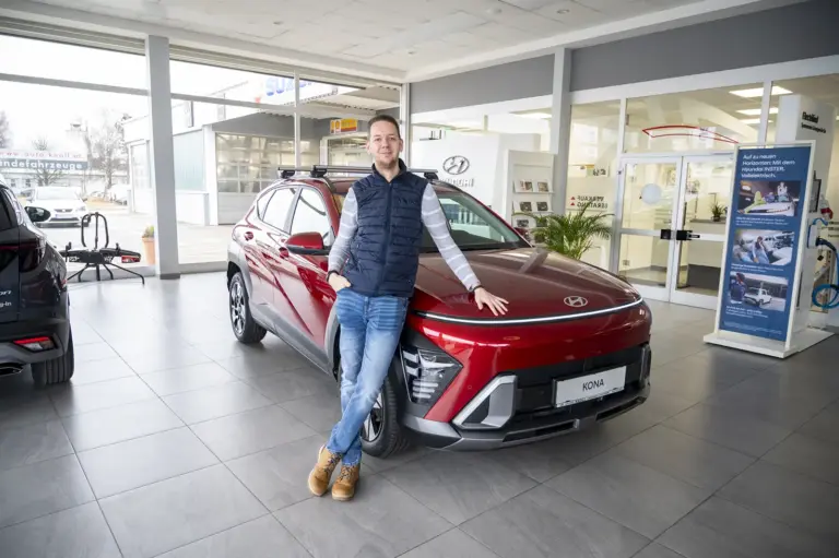 Ein Mann steht neben einem Auto.