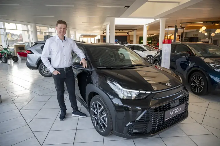 Ein Mann steht neben einem Auto.