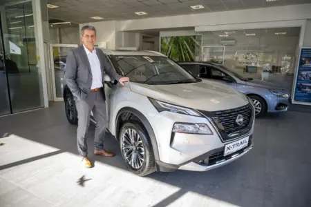 Ein Mann steht neben einem Auto.