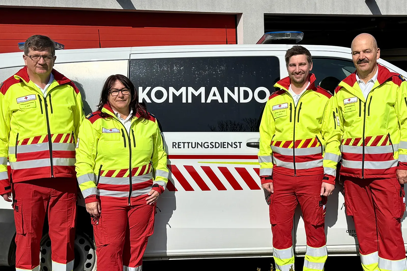 Drei Männer und eine Frau in Uniform vor einem Rettungswagen
