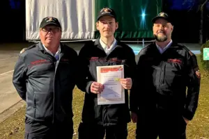 Drei Männer in Uniform präsentieren eine Urkunde