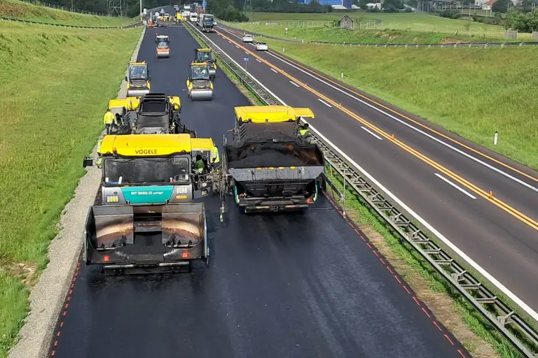 Straßensanierung um 40 Millionen Euro Mehrere Baustellenfahrzeuge auf einer frisch geteerten Straße