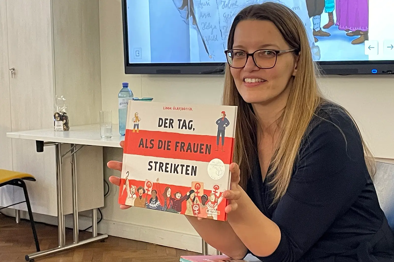 Eine Frau mit Brille und einem Bilderbuch