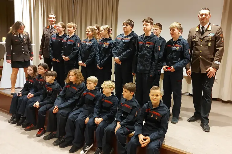 Eine große Gruppe von Kindern und Jugendlichen mit zwei Erwachsenen in Uniform