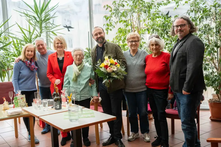 Eine Gruppe von Personen steht vor einem Tisch mit Getränken
