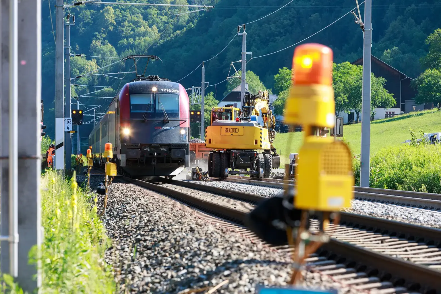 Ein Zug auf einem Gleis mit einem Baufahrzeug daneben