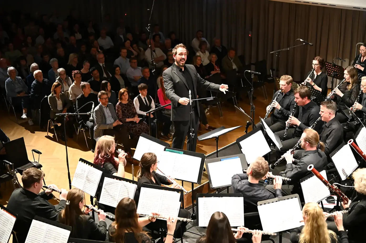 Ein Orchester mit Dirigent spielt vor einem Publikum