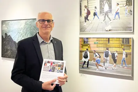 Ein Mann mit Brille vor einer Wand mit Bildern