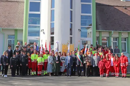 Eine große Gruppe von Personen in festlicher Kleidung mit Fahnen vor einem Gebäude