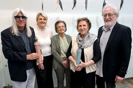 Zwei Männer und drei Frauen halten Keramikstatutetten