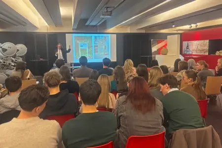 Workshop und Vortrag in Bruck Ein Vortragender mit zahlreichen ZuhörerInnen in einem großen Raum mit einer Leinwand