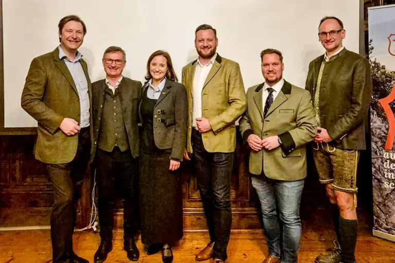 Fünf Männer und eine Frau stehen vor einer Wand