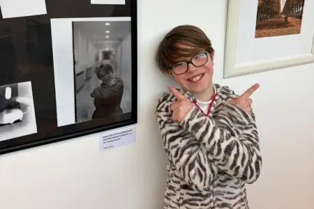 Ein junges Mädchen steht zwischen Bildern an der Wand