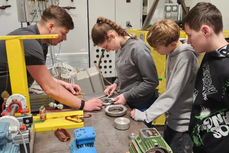 Mehrere Jugendliche arbeiten an einem Werktisch mit Elektromotoren