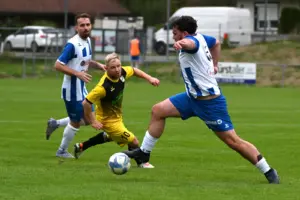 Drei Fußballspieler kämpfen um den Ball.