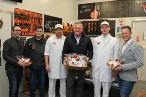 Sechs Männer mit Wurstwaren in einer Fleischerei