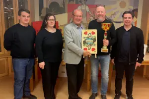 Vier Männer und eine Frau mit einem Pokal und einer großen Spielkarte