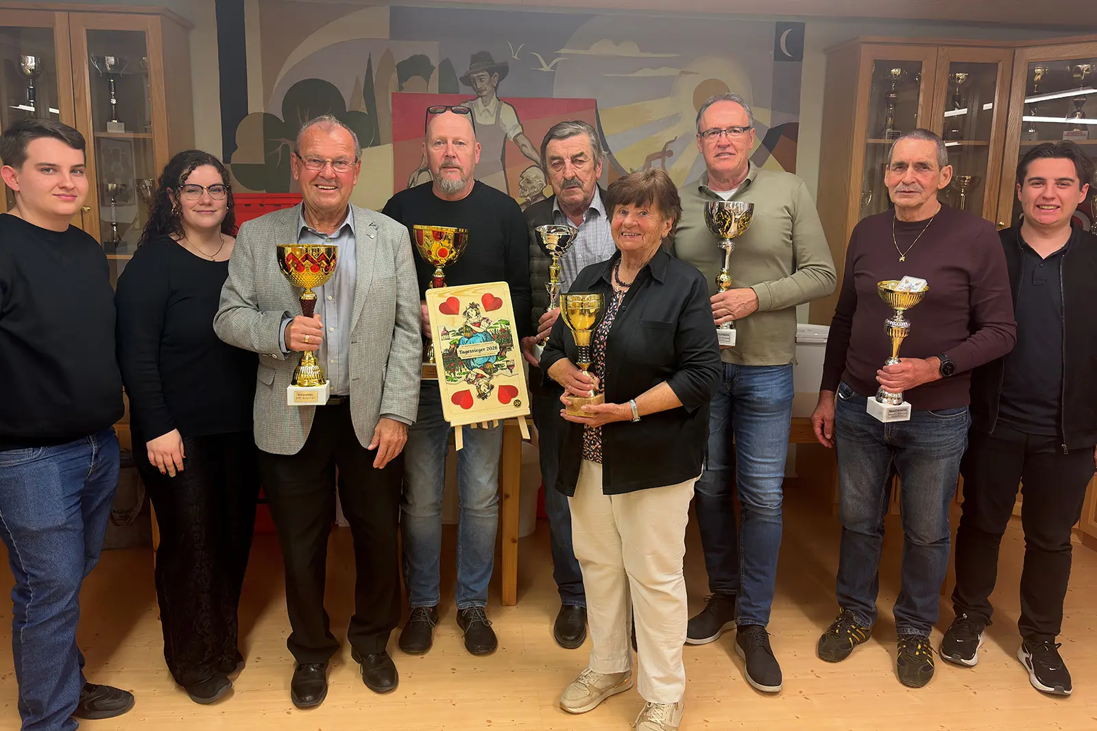 Eine Gruppe von Personen mit Pokalen und einer großen Spielkarte