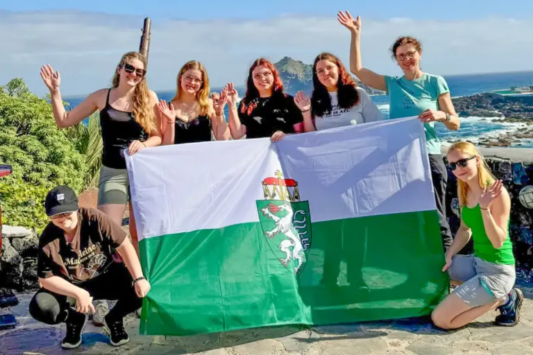 Sechs Mädchen mit einer Steiermarkfahne vor einer Meeresküste