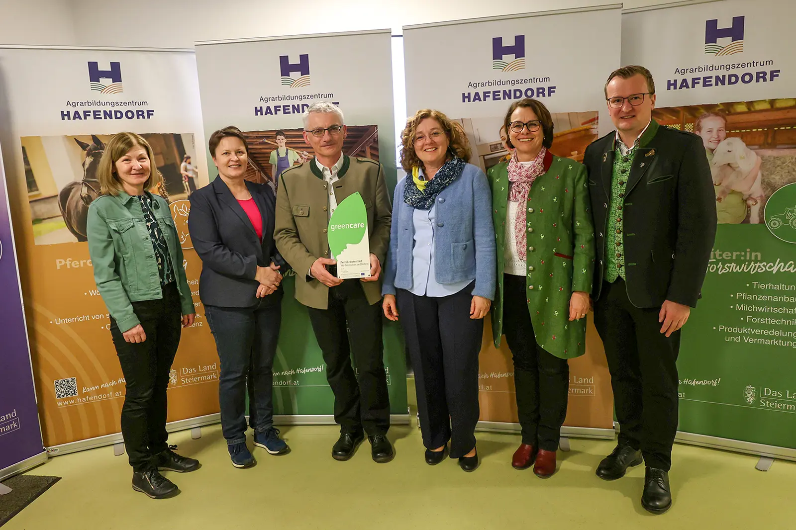 Sechs Personen präsentieren eine Trophäe