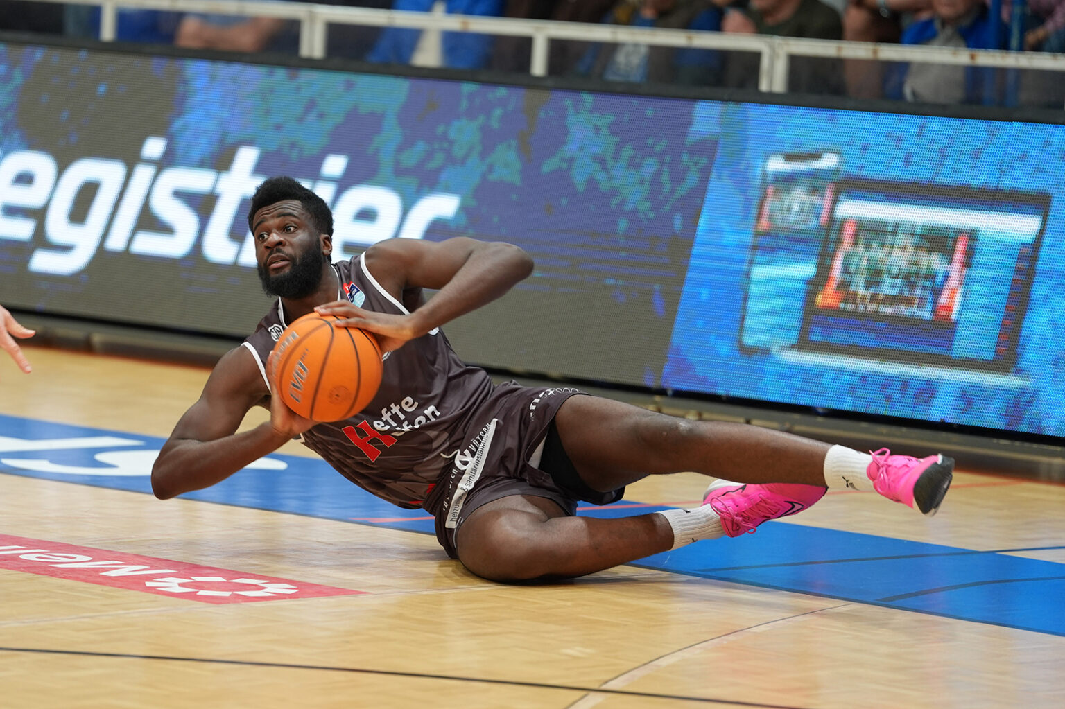 Ein Basketballspieler liegt mit dem Ball in der Hand am Boden.