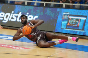 Ein Basketballspieler liegt mit dem Ball in der Hand am Boden.