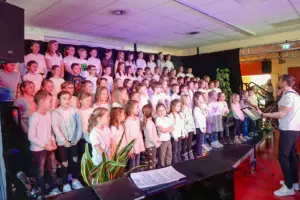 Eine große Gruppe von Kindern mit einem Gitarrenspieler auf einer Bühne