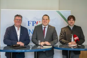 Drei Männer stehen nebeneinander bei einem Stehtisch.