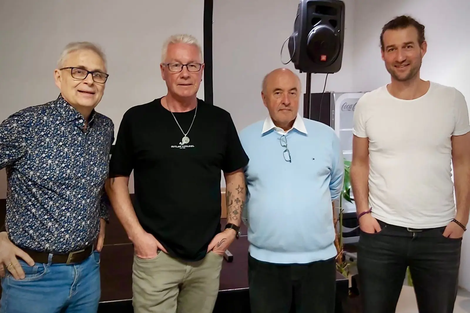 Vier Männer stehen vor einem Lautsprecher