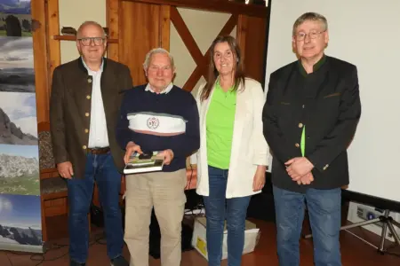 Drei Männer und eine Frau stehen vor einer Wand