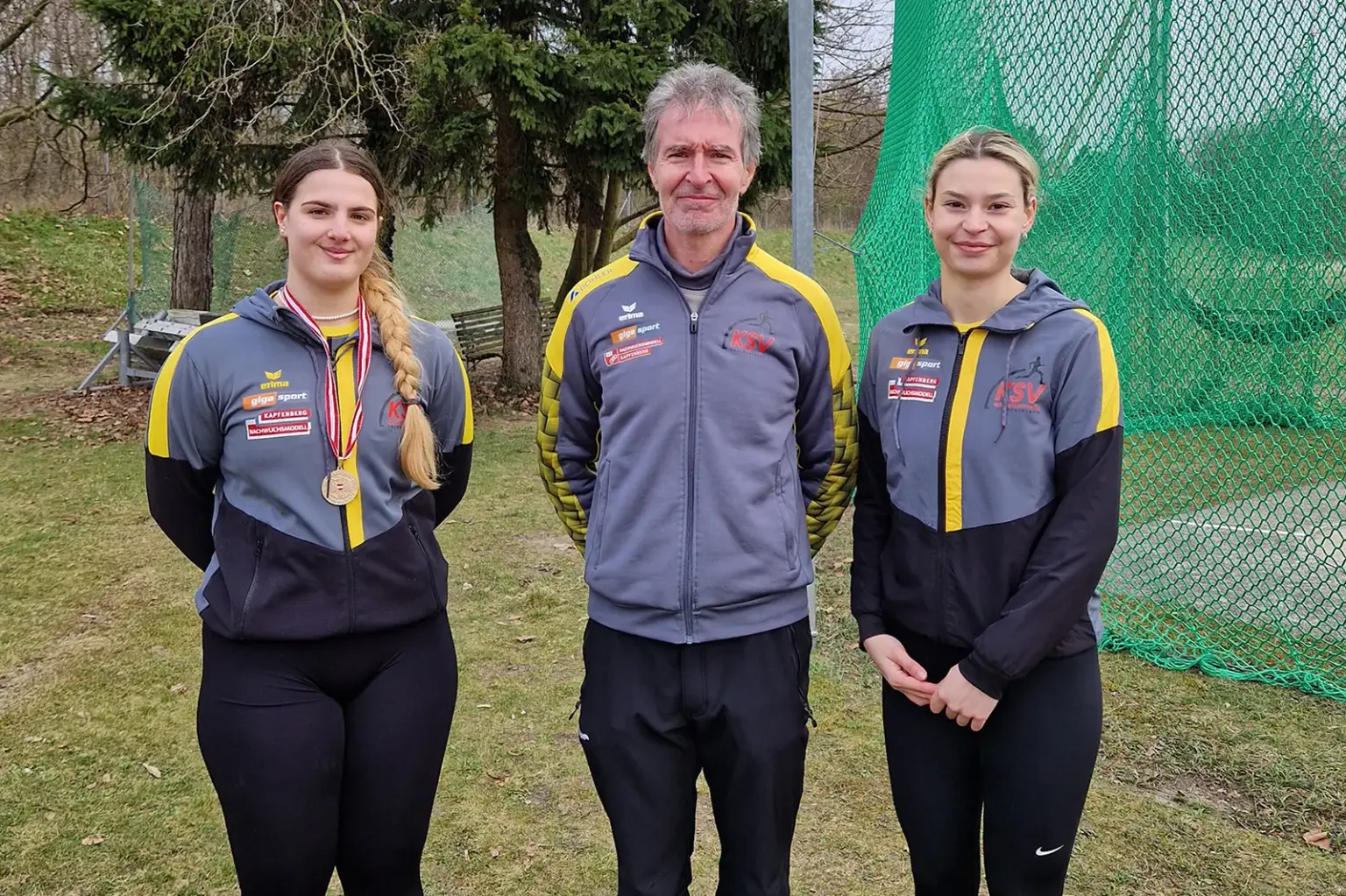 Zwei Damen und ein Mann stehen nebeneinander im Freien.