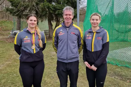 Zwei Damen und ein Mann stehen nebeneinander im Freien.